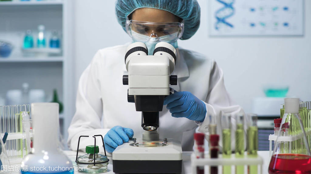 女实验室技术员在显微镜下做生物医学研究